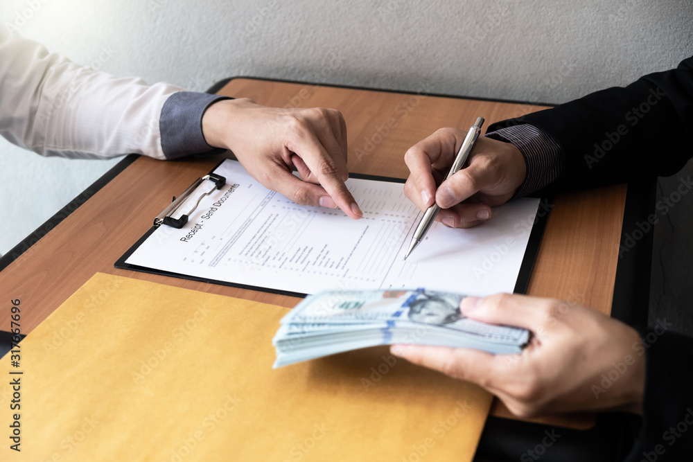 The businessman signed a contract agreement documents and receive a bribe from another businessman sitting in front at the office. The businessman signed a contract agreement documents and receive a bribe from another businessman sitting in front at the office.