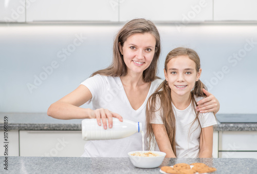 Happy family at kitchen. Mom and her young daughter have breakfast at home. Empty space for text