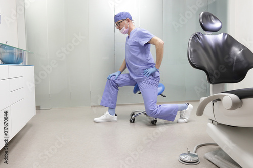 Middle age caucasian dentist stretching arms and legs .Exercises in the office environment , during break at work
