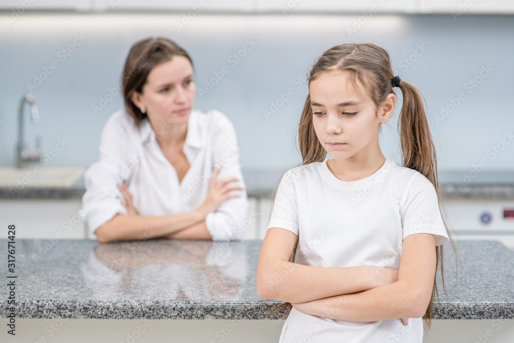 Sad girl and her mother stand at home after they quarreled. Family relationships Sad girl and her mother stand at home after they quarreled. Family relationships