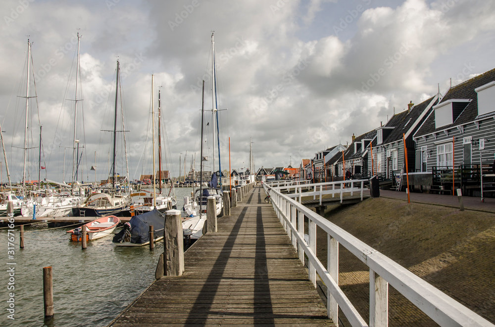 Boats on the pier, Marken, Netherlands. Beautiful pier of the island of Marken and typical wooden green houses near the waterfront in the fishing village.