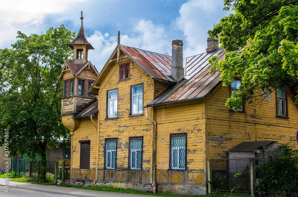 Old wooden yellow house with small tower during sunny day in summer in Riga, Latvia. Traditional Latvian Wooden Architecture.