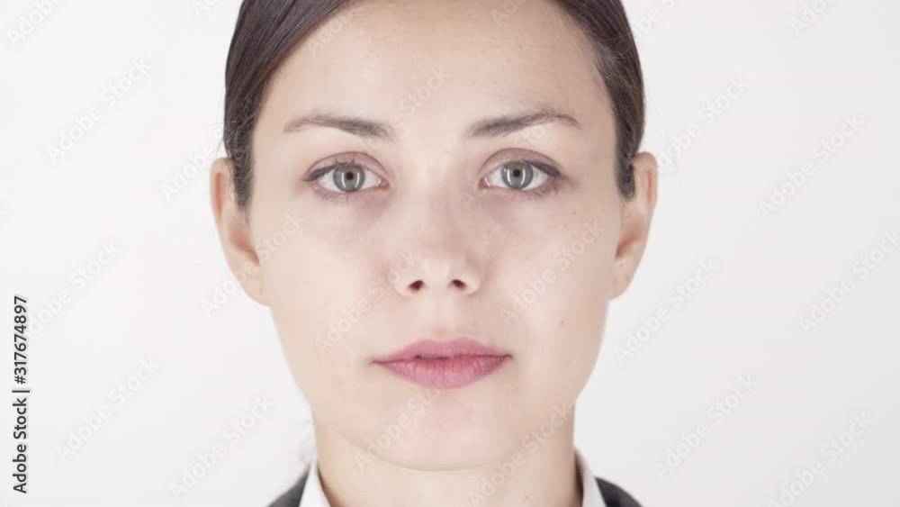 Close up of young attractive Caucasian woman looking at camera with tranquil facial expression against white background Close up of young attractive Caucasian woman looking at camera with tranquil facial expression against white background