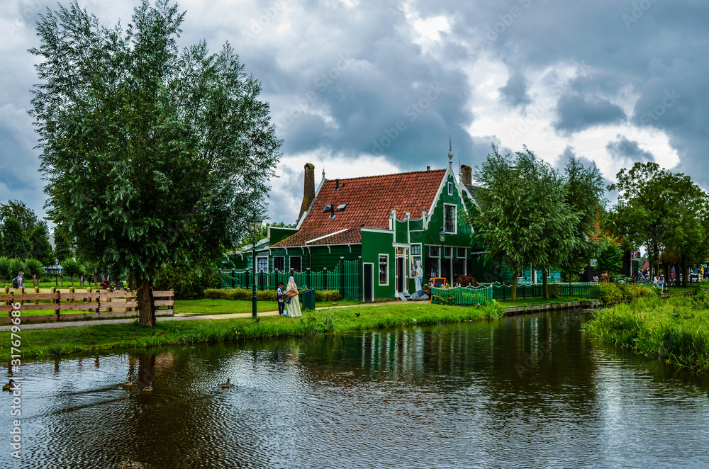Zaanse Schans, Holland, August 2019. North-east of Amsterdam is a small community located on the quay of the Zaan river. View of the charming village of wooden houses. Cloudy day.