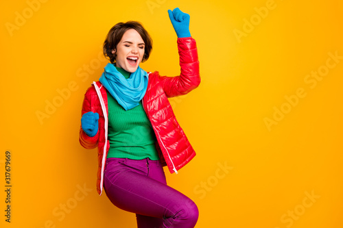 Hooray. Photo of beautiful excited lady raise hands ecstatic mood wear casual red overcoat blue scarf gloves green turtleneck trousers isolated yellow color background