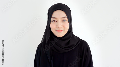 Close Up Portrait of a Young Asian Muslim Woman dressing in the traditional Hijab looking at camera smiling confident on a white background