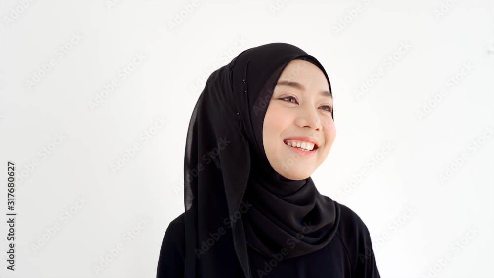 Close Up Portrait of a Young Asian Muslim Woman dressing in the traditional Hijab looking at camera smiling confident on a white background Close Up Portrait of a Young Asian Muslim Woman dressing in the traditional Hijab looking at camera smiling confident on a white background
