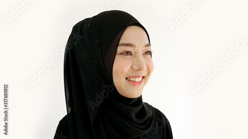 Close Up Portrait of a Young Asian Muslim Woman dressing in the traditional Hijab looking at camera smiling confident on a white background © Kittiphat
