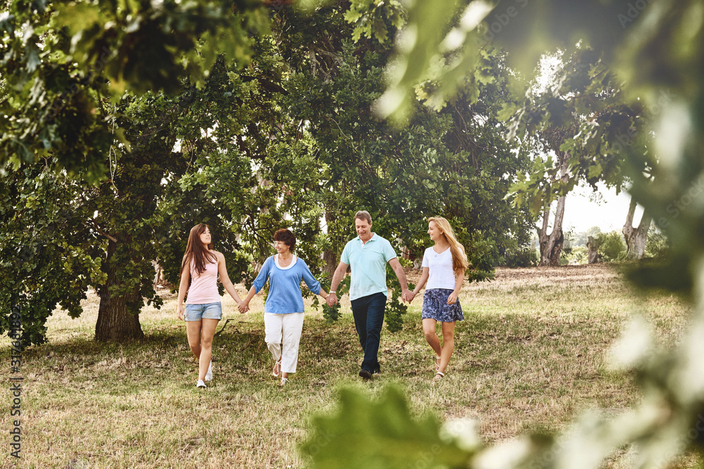 Obraz premium Family of four with adult children walking in a park