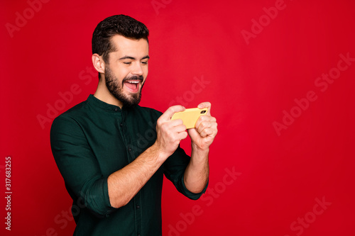 Portrait of enthusiastic funky man have break pause using cellphone play online race speed game wear casual style clothing isolated over red color background © deagreez