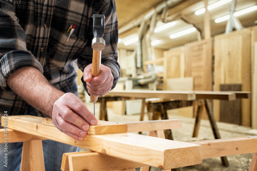 Close-up. Carpenter with hammer and nails fixes a wooden board. Construction industry, carpentry workshop. Close-up. Carpenter with hammer and nails fixes a wooden board. Construction industry, carpentry workshop.
