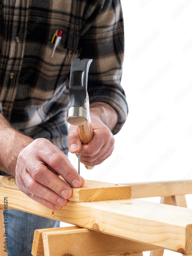 Close-up. Carpenter with hammer and nails fixes a wooden board. Construction industry. White background.