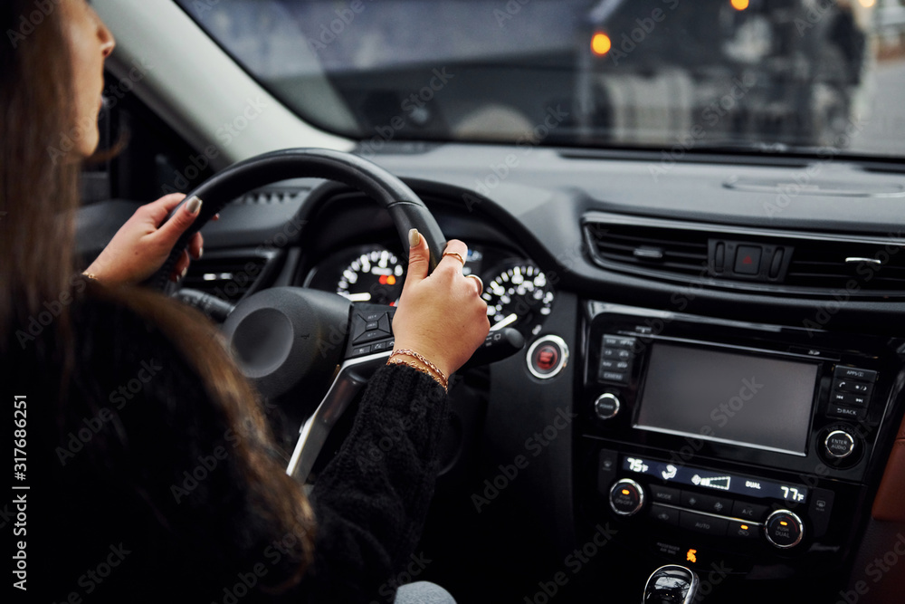 Rear view of brunette female driver that riding modern car at daytime