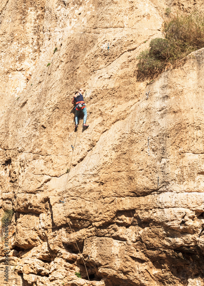 closeup of a female climber on a sheer vertical limestone cliff near ein prat in wadi qelt in the west bank