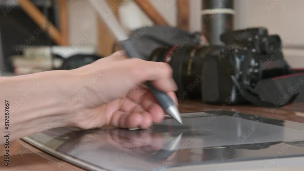 Close-up of a male designer draws on his laptop with help. graphic tablet and pen stylus Against the background of his SLR camera Close-up of a male designer draws on his laptop with help. graphic tablet and pen stylus Against the background of his SLR camera