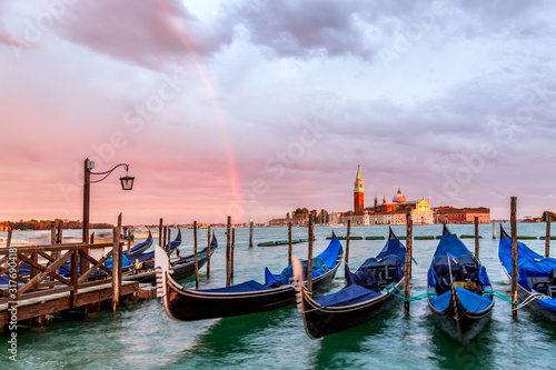 Colorful landscape with sunset sky, rainbow and gondolas parked near piazza San Marco in Venice. Church of San Giorgio Maggiore on background, Italy. Europe tourism concept.