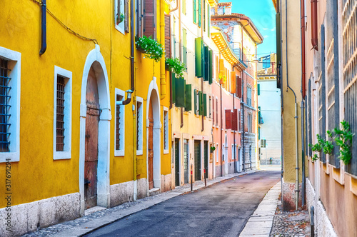 Fototapeta Naklejka Na Ścianę i Meble -  Old town cozy narrow street view with colorful houses in Verona, Italy during sunny day.
