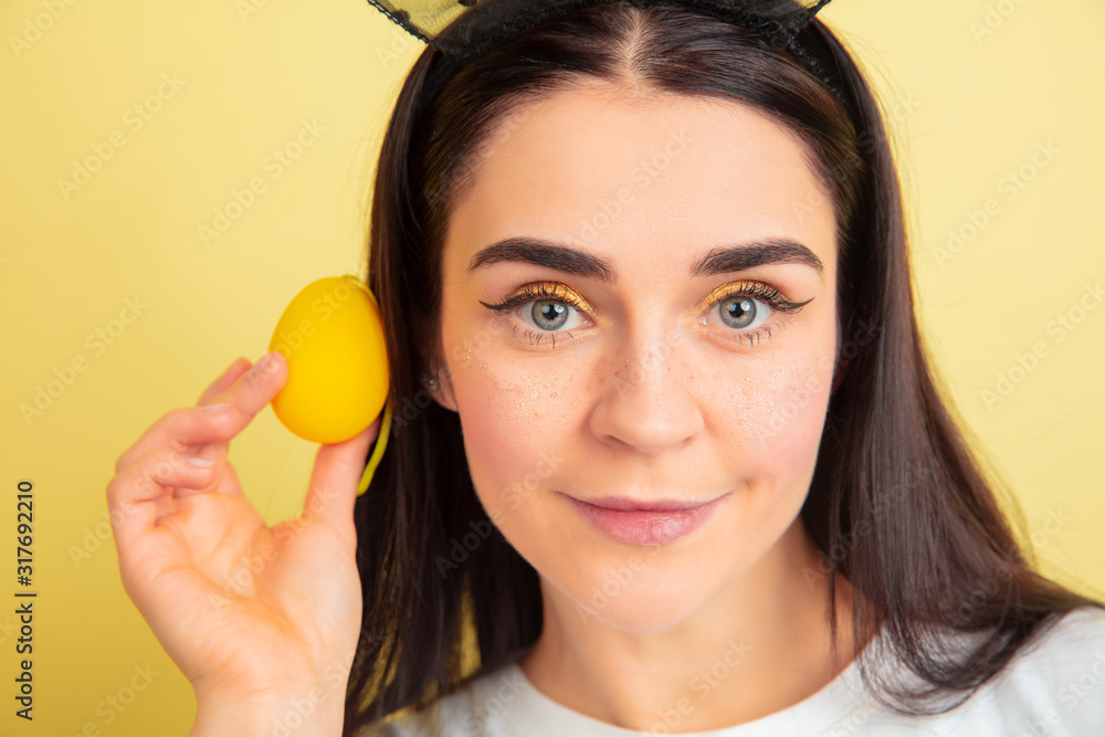 Egg hunt coming. Caucasian woman as an Easter bunny on yellow studio background. Happy easter greetings. Beautiful female model. Concept of human emotions, facial expression, holidays. Copyspace. Egg hunt coming. Caucasian woman as an Easter bunny on yellow studio background. Happy easter greetings. Beautiful female model. Concept of human emotions, facial expression, holidays. Copyspace.