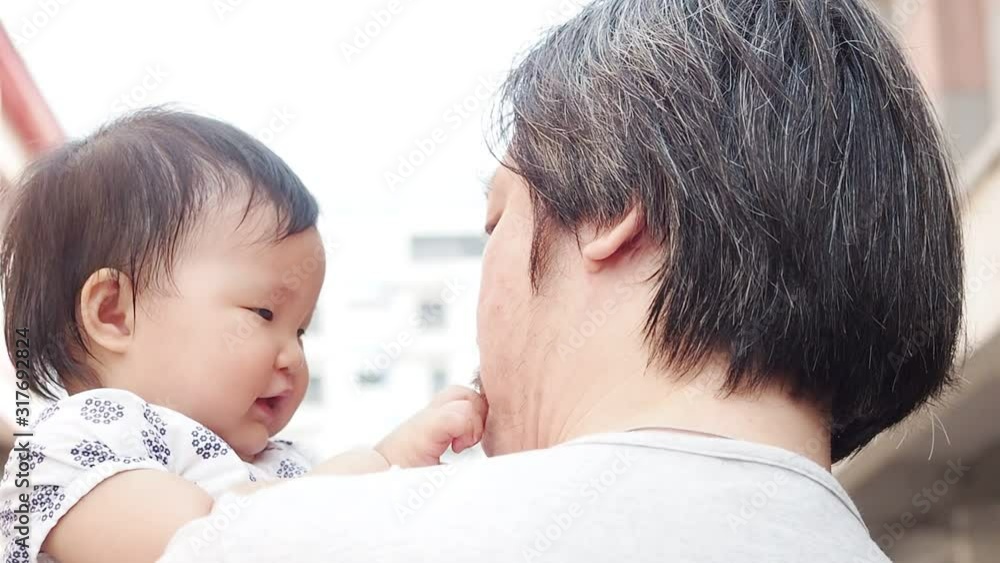 Close-up portrait of cute asian baby infant on fathers shoulder outdoors. Sweet little child smiling feeling safety on daddys hand. Responsibility and childcare. happy childhood. Close-up portrait of cute asian baby infant on fathers shoulder outdoors. Sweet little child smiling feeling safety on daddys hand. Responsibility and childcare. happy childhood.