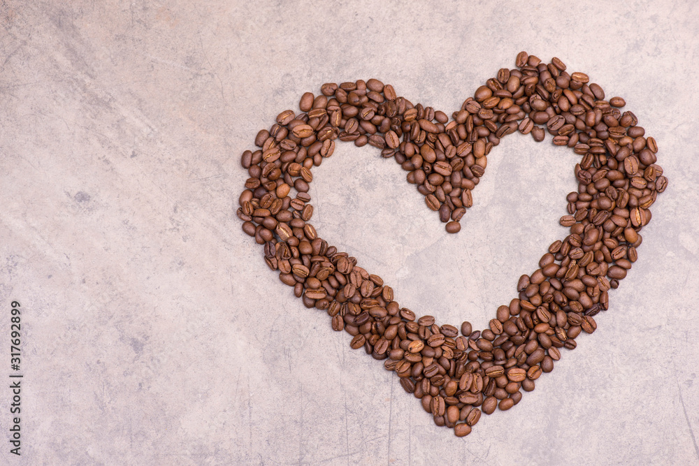 Coffee beans in the shape of a heart on a brown textured background Coffee beans in the shape of a heart on a brown textured background