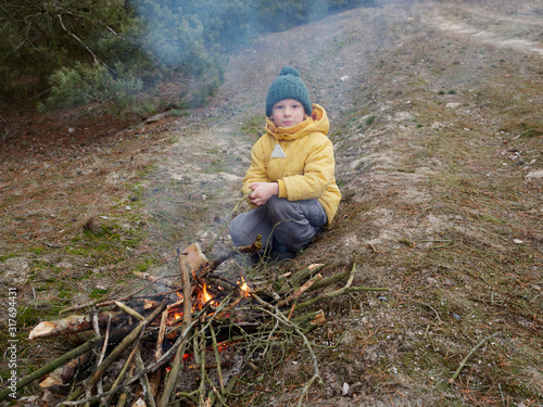 Boy prepare food on a campfire in nature