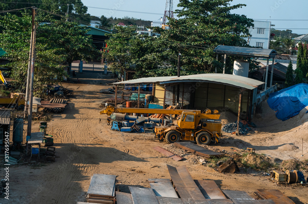 Fototapeta premium Automobile crane with risen telescopic boom outdoors. Mobile construction crane on a constructin site. Crane machine stand by waiting for work under the construction building. Heavy industry.