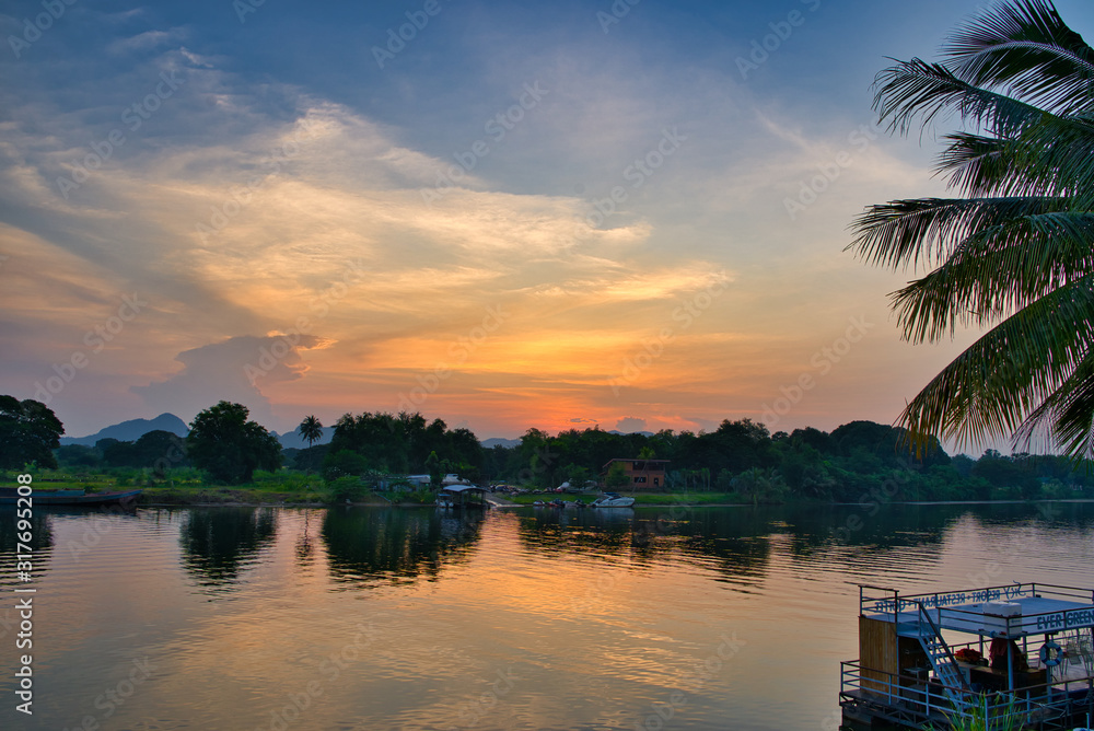 Obraz premium Calm river with some cabins on the other side of the shore as the sun goes down