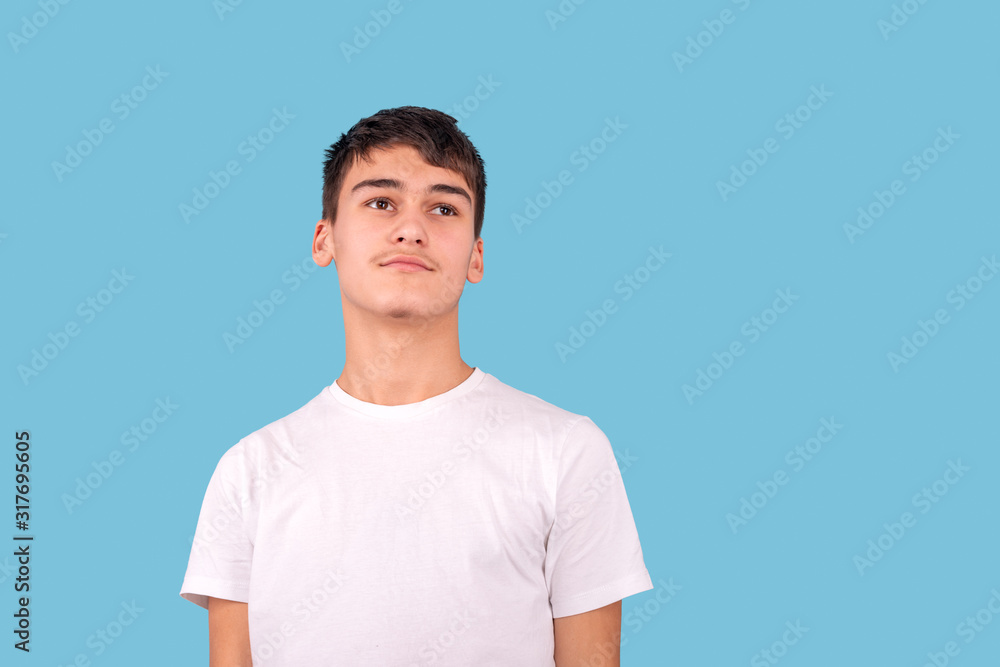 Studio shot of serious teenager brunette wearing white shirt against blue background in studio Studio shot of serious teenager brunette wearing white shirt against blue background in studio