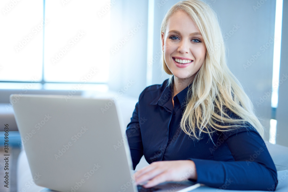 Smiling young businesswoman working on a laptop in an office Smiling young businesswoman working on a laptop in an office