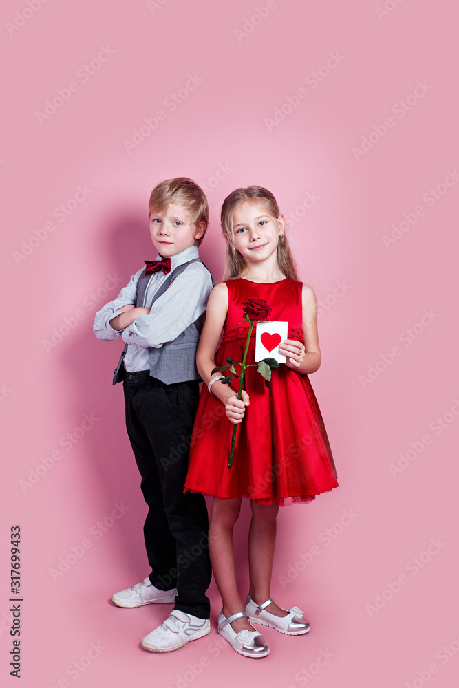 cute six year old girl with a Valentine's card in her hand and funny boy on pink background cute six year old girl with a Valentine's card in her hand and funny boy on pink background