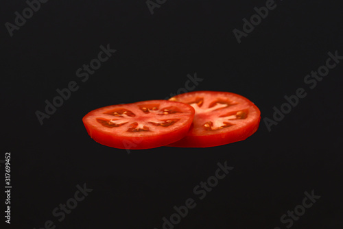 Slices of tomato isolated on black background. Copy space. Ingridients for making a hamburger.