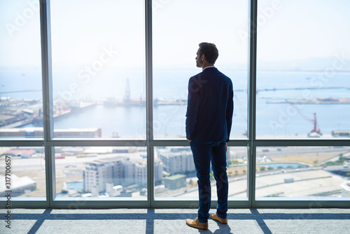 Canvastavla Businessman looking out at harbour through large windows
