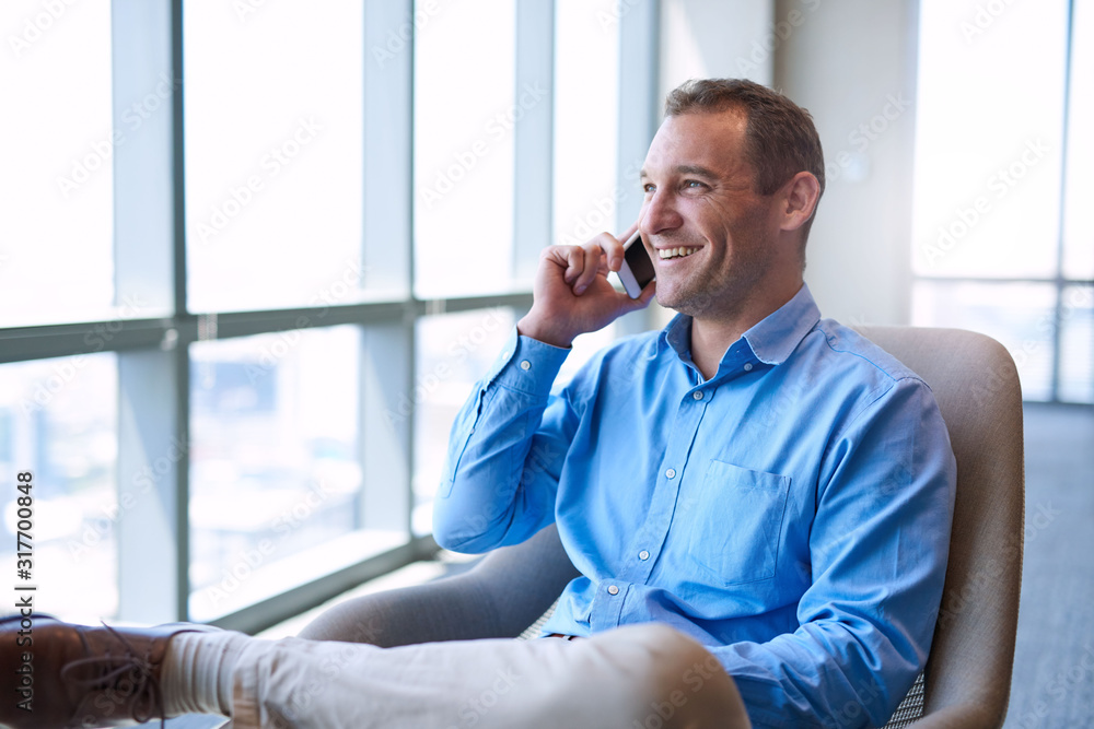Modern business executive smiling while talking on his mobile phone Modern business executive smiling while talking on his mobile phone