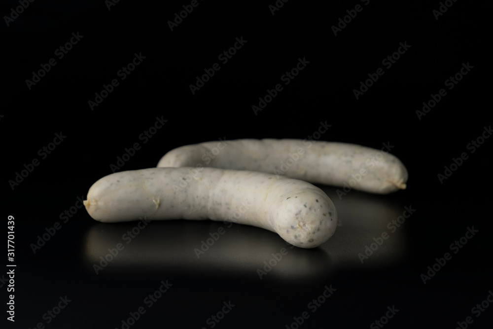 Two long white raw bratwurst sausage isolated on black background Two long white raw bratwurst sausage isolated on black background