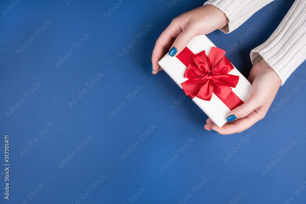 Gift box with a red bow in women's hands. Birthday present. Promotion gifts when buying. Gift box with a red bow in women's hands. Birthday present. Promotion gifts when buying.