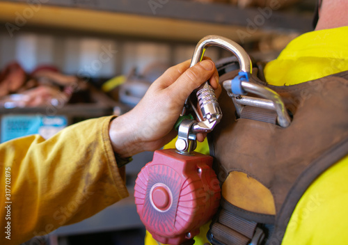 Close up construction hand clipping locking carabiner which connecting into self retractable shock absorber safety device equipment rope access body harness rescue loop prior work photo