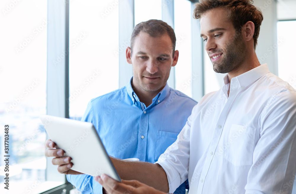 Young businessman showing colleague something on digital tablet Young businessman showing colleague something on digital tablet