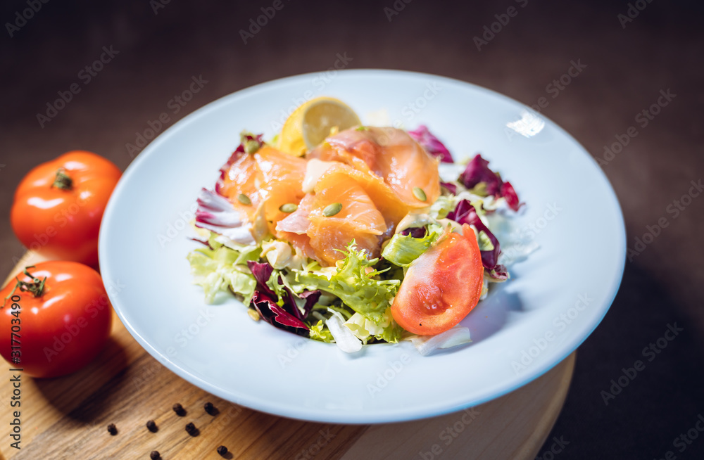 Salmon salad with lettuce, lemon, spices, seeds closeup in white plate Salmon salad with lettuce, lemon, spices, seeds closeup in white plate