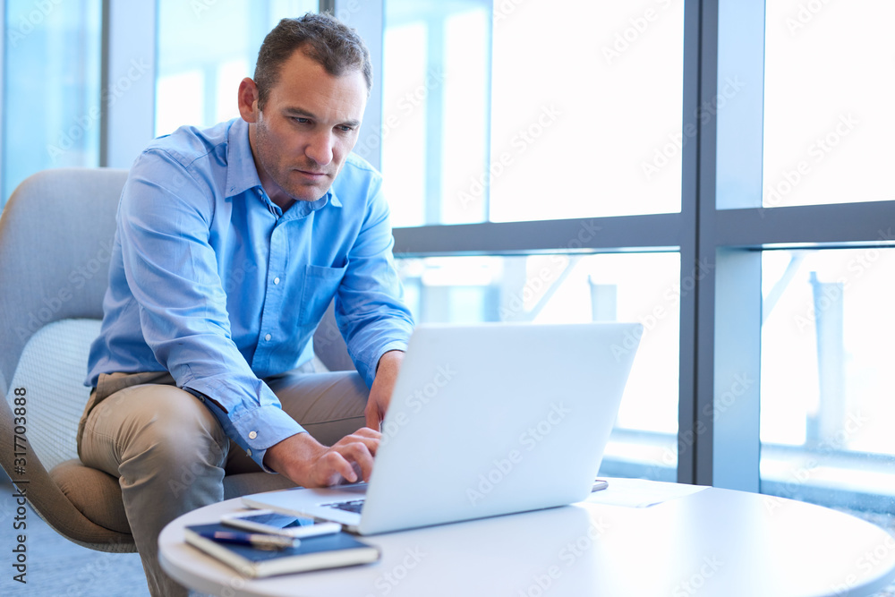 Businessman in modern office space using his laptop Businessman in modern office space using his laptop