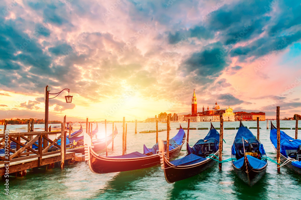 Colorful landscape with sunset sky and gondolas parked near piazza San Marco in Venice. Church of San Giorgio Maggiore on background, Italy. Europe tourism concept.