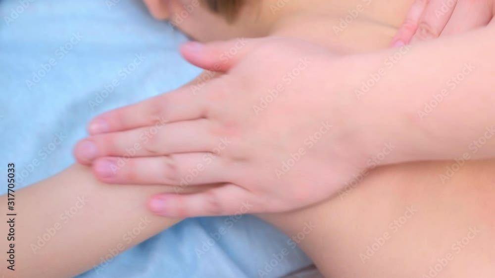 Doctor massagist making therapeutic massage to teen boy on spine, shouders and neck in clinic, closeup view. Cure medical massage, rehabilitation after injury. Medicine, treatment for children. Doctor massagist making therapeutic massage to teen boy on spine, shouders and neck in clinic, closeup view. Cure medical massage, rehabilitation after injury. Medicine, treatment for children.