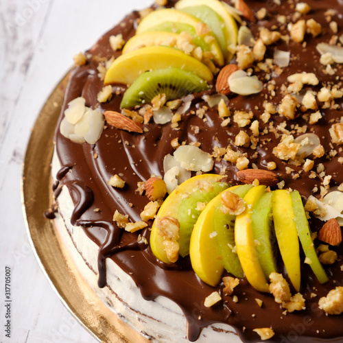 Homemade delicious sweet cake with fruits, chocolate, apple, kiwi on cup of coffee americano, white background. Organic dessert sugarless. Healthy eating.