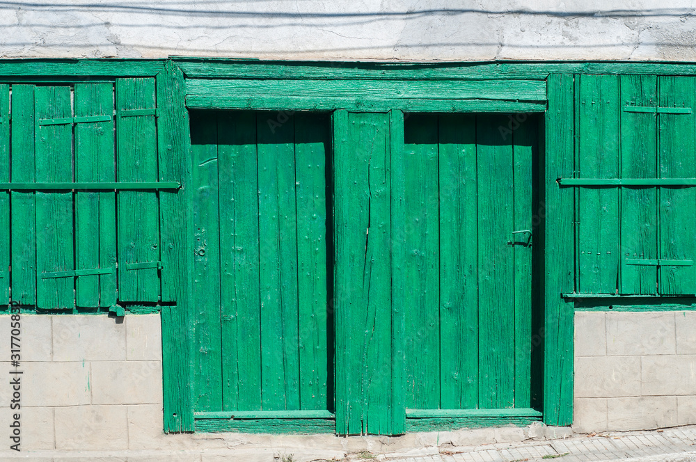 Old weathered green rural house wooden door and window shutters closeup Old weathered green rural house wooden door and window shutters closeup