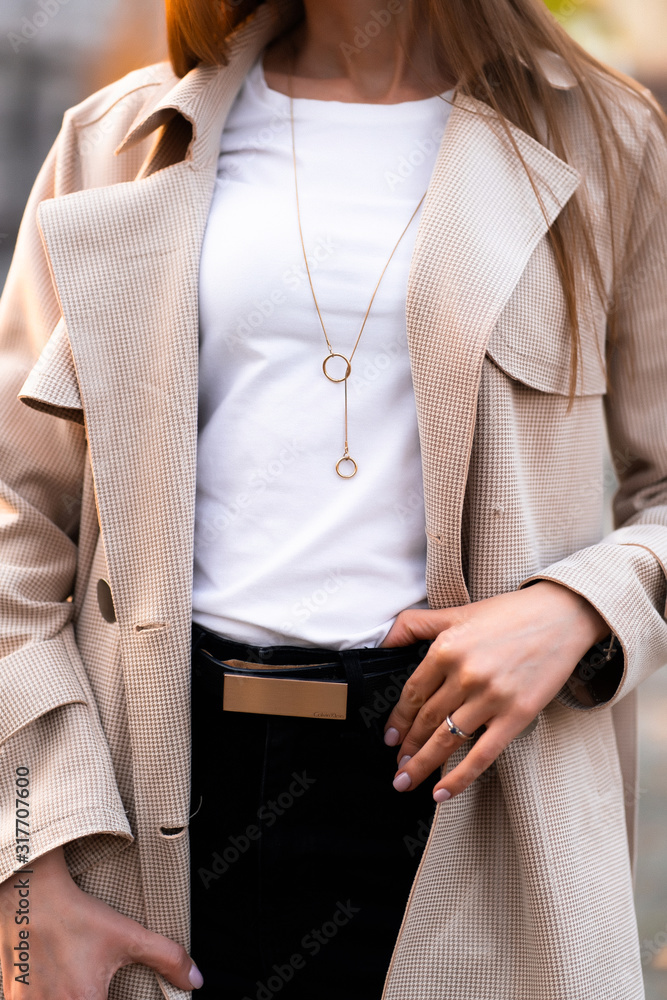 Outdoor photo of brunette lady walking on street background in autumn day.Fashion street style portrait. wearing dark casual trousers and white sweater and creamy coat.Fashion concept.