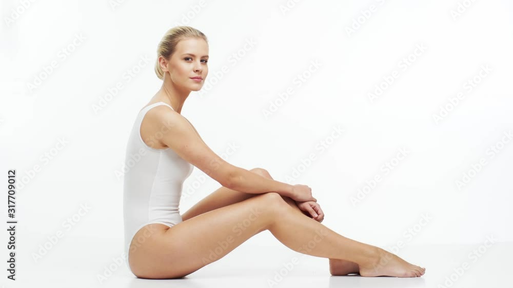 Young, beautiful, slim and healthy blond girl in white swimsuit applying skincare cream. Massage, skincare, healthcare, wrinkles removal and fitness. Young, beautiful, slim and healthy blond girl in white swimsuit applying skincare cream. Massage, skincare, healthcare, wrinkles removal and fitness.