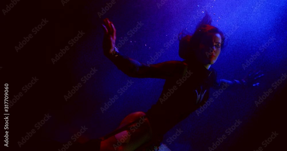 The fateful slender girl is in a dark Studio under water, wearing a body and tights in a cage, she poses. There are bubbles around it. There is a light in the background. The fateful slender girl is in a dark Studio under water, wearing a body and tights in a cage, she poses. There are bubbles around it. There is a light in the background.