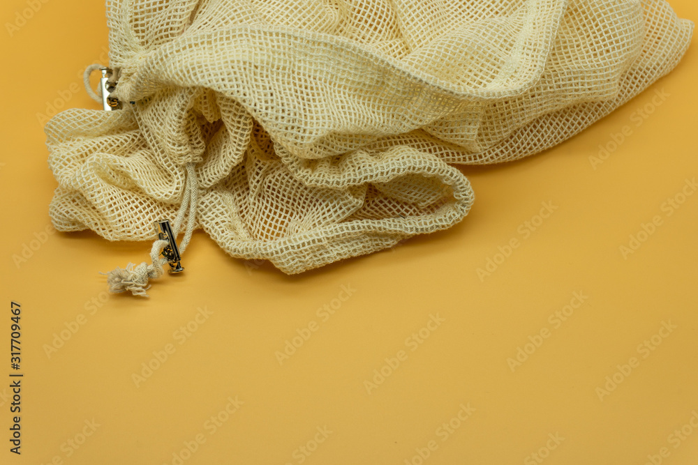 Reusable organic cotton string bag, isolated on a yellow background. Zero waste concept. Reusable organic cotton string bag, isolated on a yellow background. Zero waste concept.