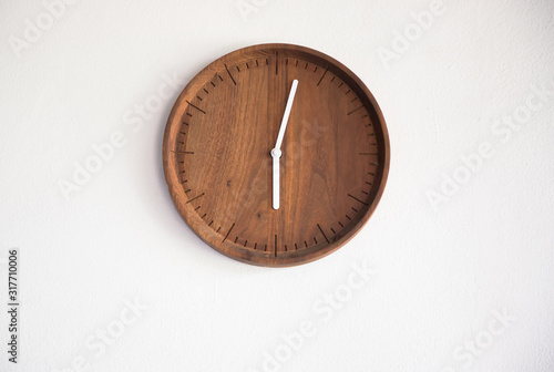 wooden clock wall on white concrete panel. time at 6 A.M. in morning.