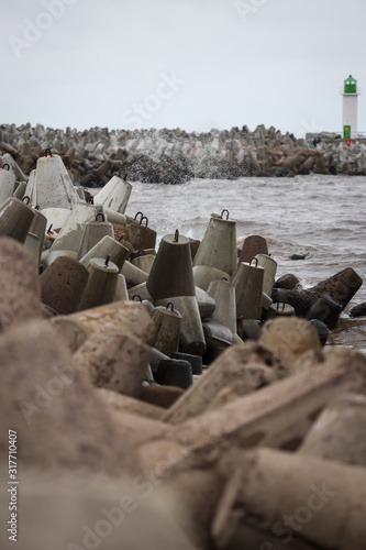 Baltic sea waves hitting stone blocks near path to ship lighthouse. Path located near Ventpils Docks. photo