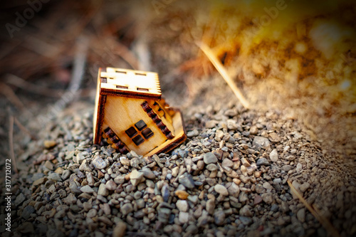 Schilderij op canvas Miniature model house stands askew in a mountain of small stones